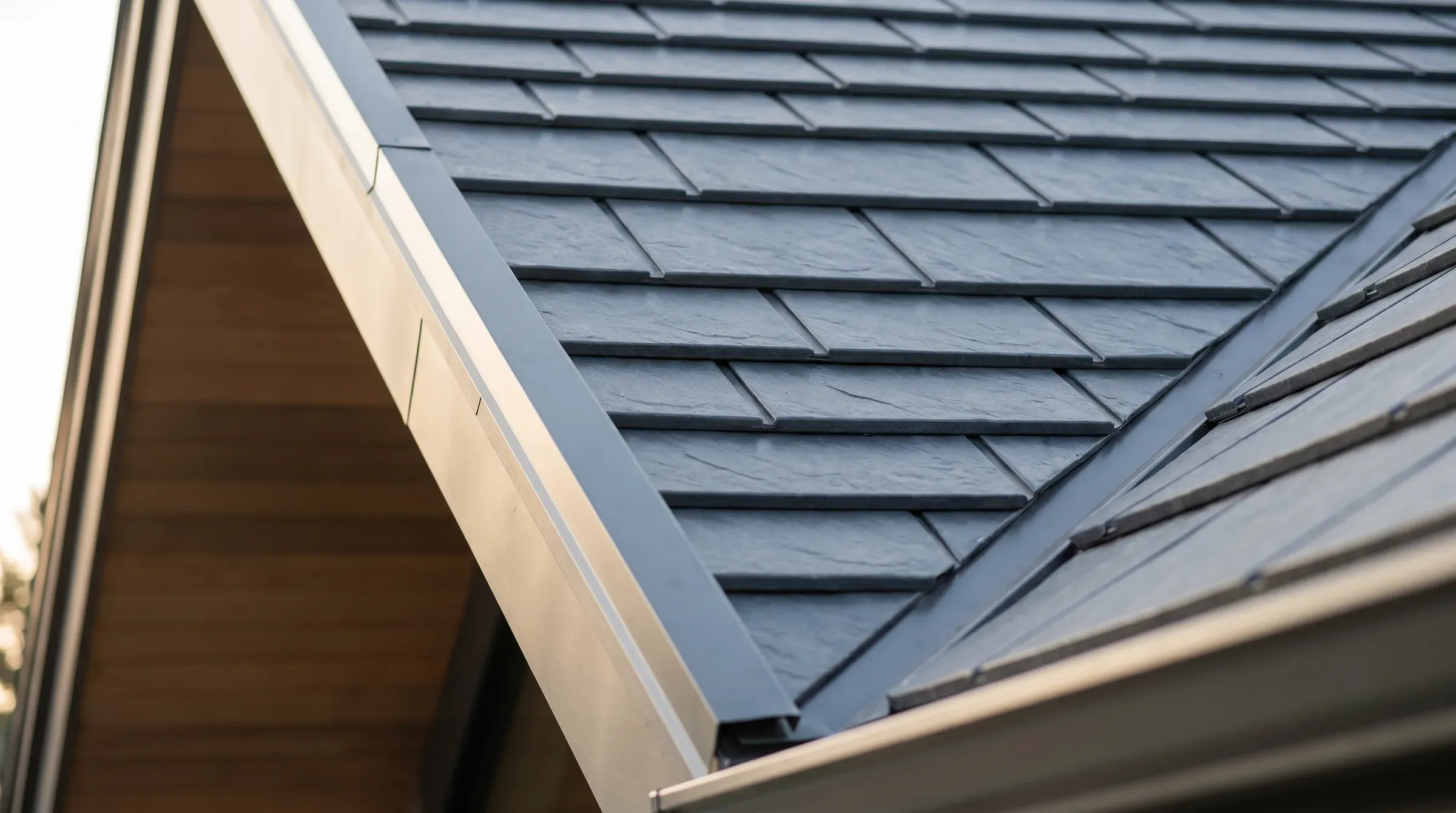 Close-up of pressed-steel Gerard-style metal roofing tiles in repeating rows with a dark charcoal finish.