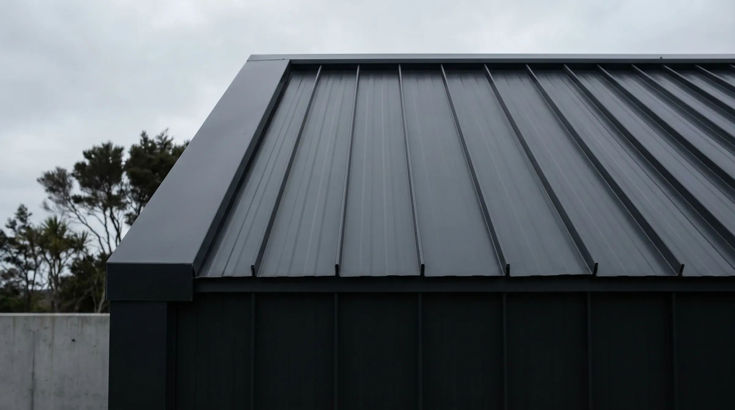 Architectural detail of dark charcoal long-run metal roofing with vertical trays and concealed fastening.